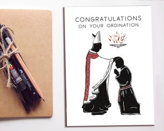 May include: A black and white illustration of a priest in a cassock and mitre laying hands on a kneeling priest. The text "CONGRATULATIONS ON YOUR ORDINATION" is at the top of the card.