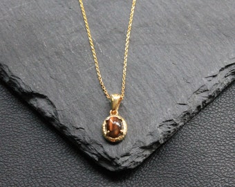 May include: A gold chain necklace with a brown oval pendant featuring a gold setting.