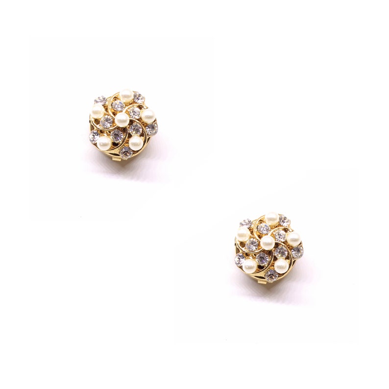 Peut inclure: Une paire de boucles d'oreilles en or avec un motif en spirale et des accents de perles blanches.