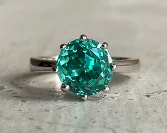 May include: A silver ring with a large, round, green gemstone set in a prong setting.