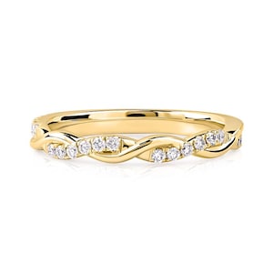 May include: A gold-colored ring with a twisted band design. The ring is adorned with small, clear gemstones set along the band. The gemstones are evenly spaced, adding sparkle to the jewelry. The ring is likely for engagement or fashion.