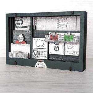 May include: A dark green framed art piece with a detailed, grayscale depiction of a border control scene. Features include a passport, stamps labeled "Denied" and "Approved," and a figure behind a desk. The text "DRAG DOCUMENTS HERE" is visible.