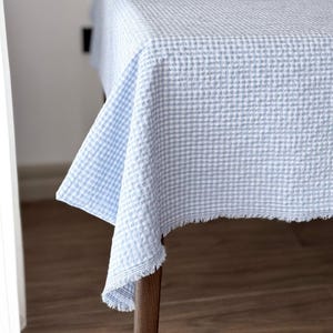 Puede incluir: Una taza de cerámica blanca con un asa negra y el texto "But First, Coffee" en negro, con una fuente de estilo manuscrito. La taza está sobre una superficie blanca.