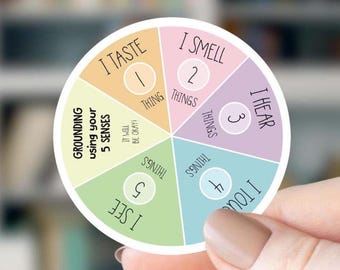 May include: A circular sticker featuring a grounding exercise with five colored segments. Text reads: Grounding using your 5 SENSES, I TASTE 1 THING, I SMELL 2 THINGS, I HEAR 3 THINGS, I TOUCH 4 THINGS, I SEE 5 THINGS, and IT WILL BE OKAY.