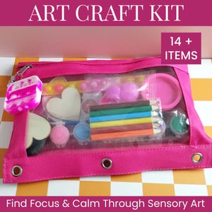 May include: A pink zippered pouch containing an art craft kit with 14+ items, including a small pink and white tie-dye pop-it toy, colored pencils, heart-shaped cutouts, small paint pots, and a yellow sensory strip, labeled ART CRAFT KIT.