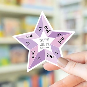 May include: A star-shaped sticker with a light purple and lavender color scheme. The sticker has the words "Breathe With Me" and "It will be okay" in the center. The words "in" and "out" are repeated around the star's points.