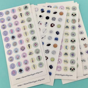 Puede incluir: Varias hojas de pegatinas con diferentes dise&ntilde;os. Una hoja tiene helados, magdalenas y galletas. Otra presenta equipamiento deportivo como balones de f&uacute;tbol y de tenis. La &uacute;ltima hoja tiene animales como gatos y tortugas. El texto "https://beconfidentlyyou.etsy.com" est&aacute; impreso en la parte inferior.