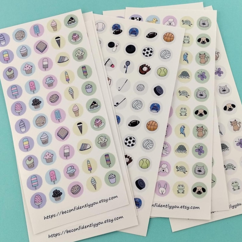 Puede incluir: Varias hojas de pegatinas con diferentes dise&ntilde;os. Una hoja tiene helados, magdalenas y galletas. Otra presenta equipamiento deportivo como balones de f&uacute;tbol y de tenis. La &uacute;ltima hoja tiene animales como gatos y tortugas. El texto "https://beconfidentlyyou.etsy.com" est&aacute; impreso en la parte inferior.