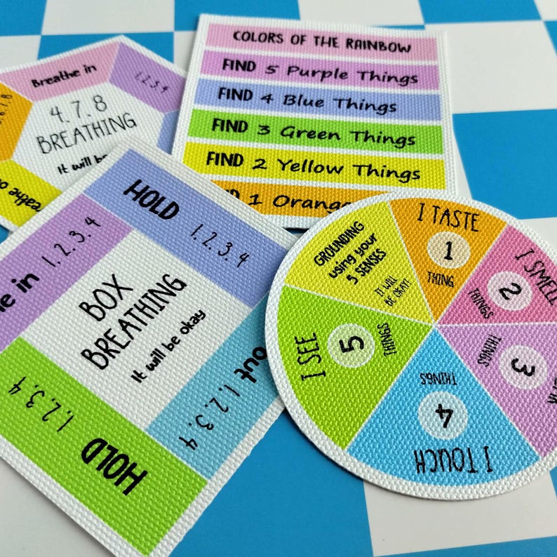 May include: Three square and circular cards featuring colorful educational graphics. One card displays 4-7-8 breathing instructions, another outlines box breathing steps, and the third is a circular chart for grounding using five senses.