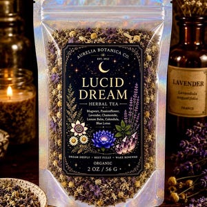 Peut inclure: Un sachet holographique de tisane Lucid Dream d'Aurelia Botanica Co. contenant 56 grammes d'herbes s&eacute;ch&eacute;es. L'&eacute;tiquette noire pr&eacute;sente un croissant de lune, des &eacute;toiles et des illustrations de fleurs et cristaux avec le texte Lucid Dream Herbal Tea.
