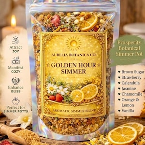May include: A holographic pouch of Aurelia Botanica Co. Golden Hour Simmer aromatic simmer blend. The label features a sun icon and lists ingredients including brown sugar, strawberry, calendula, jasmine, chamomile, orange, lemon, and vanilla.