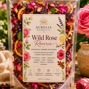 May include: A clear plastic pouch filled with a dried botanical simmer pot blend containing rose petals, orange slices, lavender, and cinnamon sticks. The label reads Aurelia Botanica Co. Wild Rose Reverie, listing ingredients and a net weight of 3 oz.