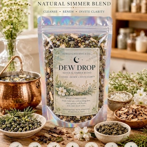 May include: A holographic pouch of Aurelia Botanica Co. Dew Drop natural simmer blend. The label features a crescent moon, floral illustrations, and text describing the scent. Below are seven circular icons detailing ingredients like juniper berries, cedarwood chips, willow bark, green tea leaves, white flower petals, resin tears, and water drop capsules.