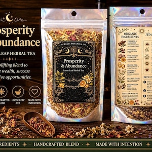 May include: Two clear, holographic-finish pouches of Aurelia Botanica Co. Prosperity & Abundance loose leaf herbal tea. The front label features celestial graphics and text, while the back label lists organic ingredients and brew instructions.