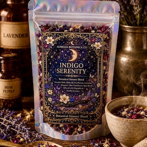 May include: A holographic pouch containing Indigo Serenity botanical simmer blend, featuring jasmine buds, butterfly pea flower, lavender, mugwort, blue cornflower, and rose petals. The label displays a crescent moon and floral illustrations.