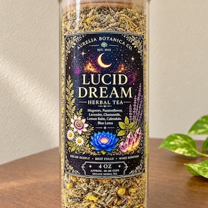 Peut inclure: Un bocal en verre transparent rempli de tisane en vrac, surmont&eacute; d'un couvercle en bambou. L'&eacute;tiquette indique Aurelia Botanica Co. Lucid Dream Herbal Tea, avec des ingr&eacute;dients comme l'armoise, la lavande et le lotus bleu, poids 113 grammes.