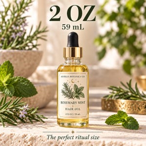 K&ouml;nnte beinhalten: Eine klare Glasflasche mit Rosemary Mint Haar&ouml;l von Aurelia Botanica Co. mit goldenem Tropfverschluss. Das Etikett zeigt botanische Illustrationen von Rosmarin und Minze, eine Mondsichel und den Text 59 mL. Das &Ouml;l ist goldgelb gef&auml;rbt.