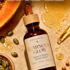 K&ouml;nnte beinhalten: Eine braune Glasflasche Luminous Glow Papaya & K&uuml;rbis Enzym Serum mit einer Pipette und einem Korkverschluss. Das Bild enth&auml;lt Papaya, K&uuml;rbis und K&uuml;rbiskerne. Text: Hydratisiert, Gl&auml;ttet, Stellt den Glanz wieder her, 60 ml e.