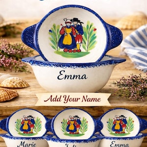 Peut inclure: Bols bretons blancs avec des bords mouchetés bleus, représentant une illustration d'un couple breton traditionnel. Les bols sont personnalisables avec des noms comme "Emma", "Marie" et "Julien". Le texte "Breton Bowls - Customizable!" est affiché en haut.