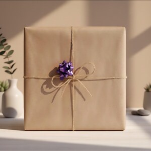 May include: A square gift box wrapped in plain light brown paper. The package is tied with thin, natural-colored twine arranged in a simple bow. A small, shiny, metallic purple decorative bow is attached to the center of the twine knot.