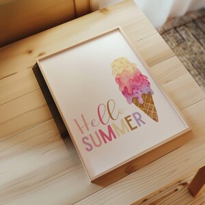 May include: A framed print with a watercolor illustration of a melting ice cream cone in pink, yellow, and purple colors. The text "Hello Summer" is written in a pink, yellow, and purple font.