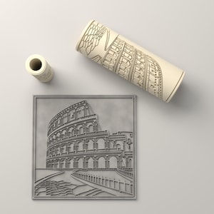 Pode incluir: Uma peça de arte de parede quadrada cinzenta com um relevo detalhado do Coliseu romano, acompanhada por um tubo cilíndrico de cor creme que exibe um desenho arquitetónico de linhas correspondente da mesma estrutura na superfície.