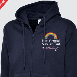 Könnte beinhalten: Dunkelblauer Kapuzenpullover mit Reißverschluss, einem Regenbogen, dem Text "Name des Krankenhauses, Bereichs oder Textes" und dem Namen "Anslie" in Rosa.