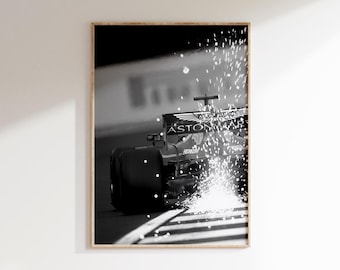 Puede incluir: Impresión enmarcada en blanco y negro de un coche de carreras de Fórmula 1 en movimiento. El coche está en una pista, con chispas saliendo de las ruedas. El logotipo de Aston Martin es visible.