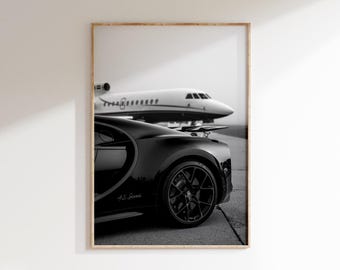 Op de afbeelding: Zwart-wit ingelijste print met een zwarte sportwagen met de tekst "42 Secs" en een privéjet op de achtergrond. De afbeelding is een monochrome foto.