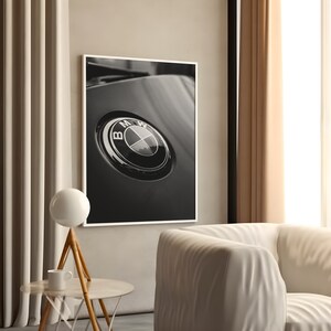 Puede incluir: Impresi&oacute;n enmarcada en blanco y negro que presenta un primer plano de un emblema de BMW. El emblema es circular con un borde plateado y un dise&ntilde;o interior en blanco y negro. La impresi&oacute;n se muestra en una pared de color neutro.