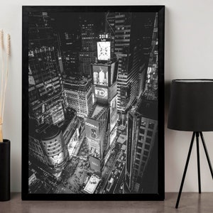 Puede incluir: Impresi&oacute;n enmarcada en blanco y negro de Times Square de noche, con vallas publicitarias iluminadas y rascacielos. La imagen captura la vibrante energ&iacute;a de la ciudad, con el a&ntilde;o 2018 visible. Una pieza de decoraci&oacute;n moderna.