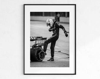 May include: Monochrome framed print of a Formula 1 driver in a racing suit and helmet, leaning on a tyre. The car's rear wing displays "Claro" and "Esso" logos. The driver is wearing a helmet with a complex design.