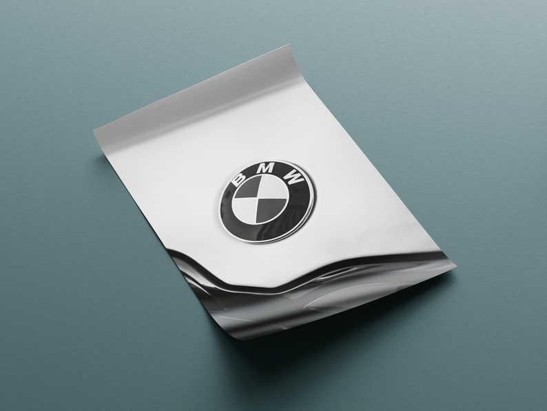 May include: A glossy white surface with a BMW emblem, featuring a black and white circular logo with the letters "BMW". The surface is slightly curved, with a dark blue-green background.