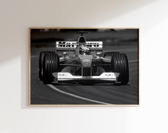 May include: Black and white framed print of a Formula 1 race car speeding around a track. The car is red and white with sponsor logos, including "FedEx" and "Marlboro." The driver is visible in the cockpit, wearing a helmet. The image is a medium shot.