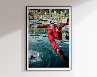 May include: A framed photograph shows a person in a red racing suit with an HP logo jumping into the water. The person is mid-air, arms outstretched, with a second person in a red suit visible in the water below. The background features a harbor with boats.