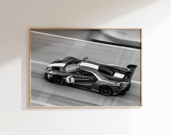 Op de afbeelding: Zwart-wit ingelijste print van een Ford GT raceauto op een circuit. De auto, met een witte streep en nummer 1, is in beweging vastgelegd. De afbeelding is ingelijst.