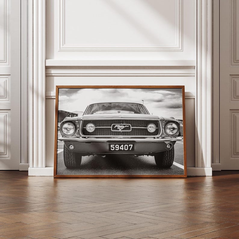 Pode incluir: Impress&atilde;o emoldurada em preto e branco de um cl&aacute;ssico Ford Mustang. O carro est&aacute; centrado, mostrando a frente com far&oacute;is, grelha e placa de matr&iacute;cula "59407". A imagem est&aacute; numa moldura de madeira, contra uma parede branca.