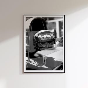 May include: Framed monochrome print featuring a Formula 1 driver in a Ferrari. The driver is wearing a helmet with the Marlboro logo. The image is a close-up of the driver in the car's cockpit.