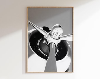 May include: Framed monochrome print featuring an airplane propeller. The silver blades radiate from a central hub, set against a black and silver engine housing. The image is a close-up, highlighting the details of the aircraft.
