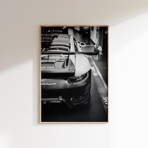 May include: Black and white framed print of a sports car's rear. The car has a spoiler and the text "ClubSport" is visible. The image is in a garage setting with a "Pit-Lane" marking on the floor.