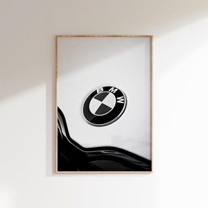May include: A framed print featuring a close-up of a BMW emblem. The emblem is a black and white circular logo with the letters "BMW" and a propeller design. The print captures the sleek lines of a car's body.