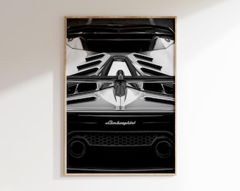 Op de afbeelding: Zwart-wit ingelijste print van een Lamborghini auto. De afbeelding toont de achterkant van de auto, met de achterlichten, uitlaatpijpen en het logo van het merk. De print wordt weergegeven op een witte muur.