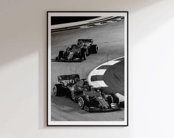May include: A black and white framed wall art print depicting two Formula 1 race cars navigating a curved track. The lead car is marked with the number 5, while the trailing car is marked with the number 16. The scene captures the high-speed action.