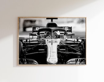 Puede incluir: Fotografía en blanco y negro enmarcada de un coche de carreras de Fórmula 1. La imagen destaca la parte delantera del vehículo, enfatizando su diseño aerodinámico y el habitáculo del piloto. El fondo está borroso, creando una sensación de velocidad.