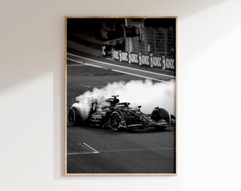May include: Black and white framed print of a Formula 1 race car speeding on a track, with smoke billowing from the tires. The car has sponsor logos and is in motion. The image is set against a backdrop of a race track.