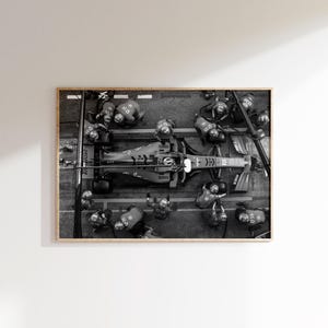 May include: Black and white photograph of a Formula 1 race car in a pit stop. The car is surrounded by crew members in matching uniforms. The image is framed in a wooden border.
