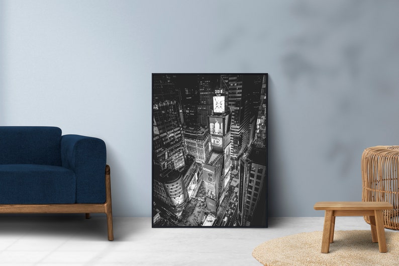 Puede incluir: Impresi&oacute;n en blanco y negro de Times Square por la noche. La imagen captura las luces brillantes y los rascacielos de este emblem&aacute;tico lugar de Nueva York. La obra de arte se exhibe en un sal&oacute;n, apoyada contra una pared.