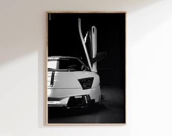 Op de afbeelding: Zwart-witfoto van een witte sportwagen met een openstaande deur. De auto heeft een gestroomlijnd ontwerp met een laag profiel en een opvallende voorkant. De deur is open en onthult het interieur. De achtergrond is donker, wat de vorm van de auto benadrukt.