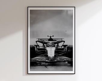 Peut inclure: Une impression d'art mural encadrée en noir et blanc représentant une voiture de course de Formule 1 vue de face sur une piste. Le véhicule présente un design aérodynamique profilé avec une structure de sécurité halo et un aileron avant.