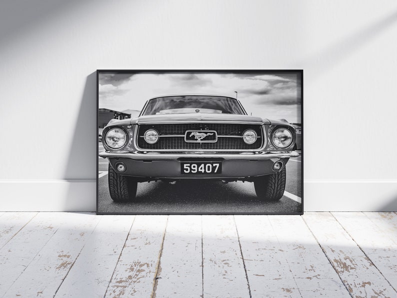 Pode incluir: Impress&atilde;o emoldurada em preto e branco de um Ford Mustang cl&aacute;ssico. O carro tem uma proeminente grelha dianteira com o emblema Mustang, far&oacute;is redondos e uma placa de matr&iacute;cula que diz "59407". A imagem &eacute; definida contra um c&eacute;u nublado.
